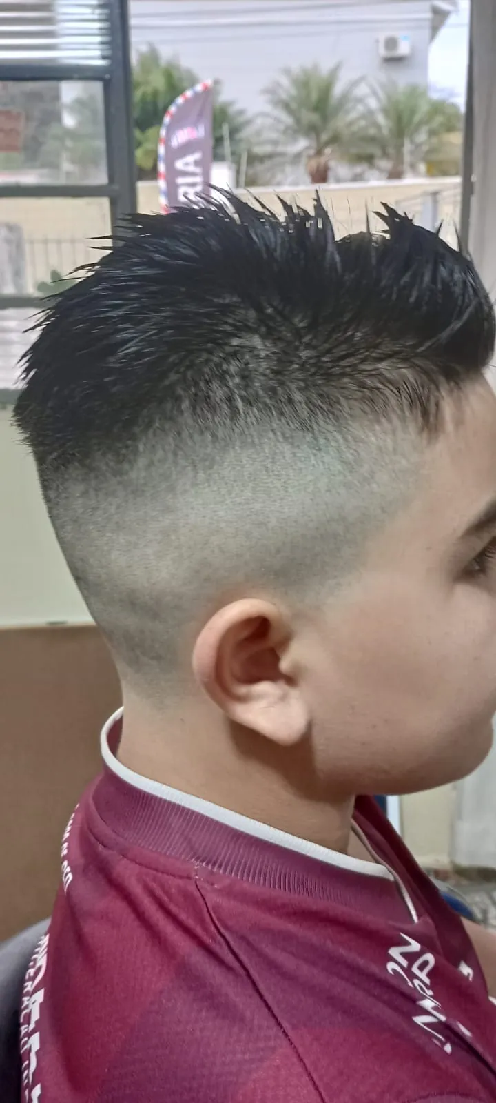 Corte infantil com topo espetado e laterais em degradê, visto de lado